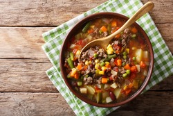 Vegetable soup with ground beef close-up in a bowl on the table. Horizontal top view from above