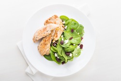 Chicken with spinach salad on white wooden background top view. Healthy food.