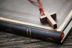 Closeup of simple wooden Christian cross necklace on holy Bible