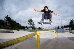 Skateboarder doing a ollie over the rail at the skate park.