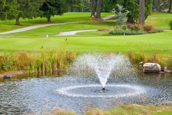 Beautiful golf place with gorgeous green, pond and fountain.