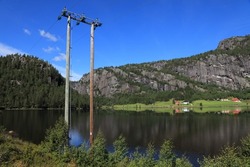 Lake side village in Setesdal, Norway. Wooden electric pole in Agder region. Electrical grid power lines.