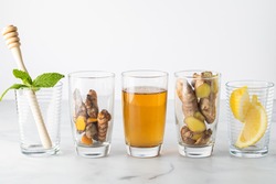 A row of clear glasses with various ingredients used in making infused Green tea.