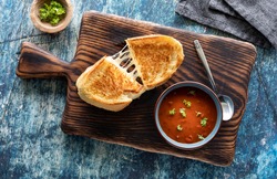 Top down view of a grilled cheese sandwich with tomato soup, ready for eating.