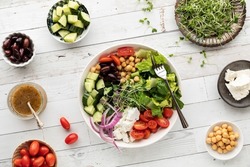 Top down view of a Greek salad bowl with separate bowls of the ingredients.