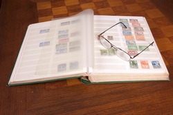Pair of glasses sitting on a philatelic stamp collection album