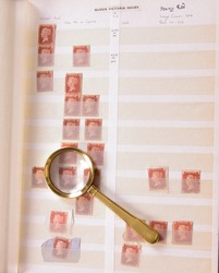 Magnifying glass laying on philatelic stamp album