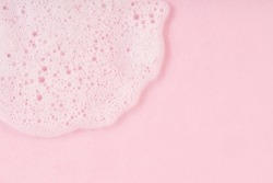 White cleanser foam drop on pink background. Soap, shower gel, shampoo foam texture closeup