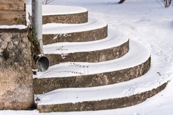 Snowy stairs with round steps at the entrance to the house.