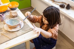 Cute little kid playing with modeling clay in pottery workshop, craft and clay art, child creative activities, education in Arts