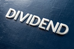 the word dividend laid by volumetric silver metal letters on gloss painted board background with selective focus