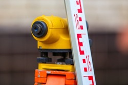 close-up view of cheap geodesy level device with tower ruler outdoors at daylight