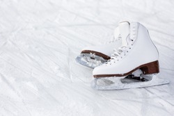 close up of white leather figure skates and copy space over ice background with marks from skating
