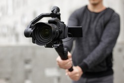 filmmaking, videography, hobby and creativity concept - close up of modern dslr camera on 3-axis gimbal in male hands