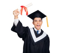 Excited young man in  black graduation gown and cap holding a diploma 