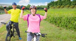 Happy Asian healthy senior couple exercising with bicycles