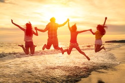 group of happy young people jumping on the beach