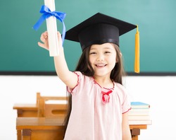 Portrait of  cute schoolgirl with graduation hat in classroom
