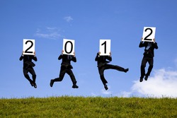 businessman holding 2012 billboard and jumping on the green field