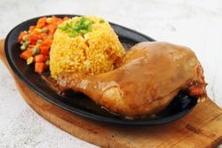 Photo of freshly cooked fried chicken with gravy, fried rice and vegetables served on a hot plate.