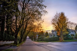 Serene suburban street with houses and golden trees at sunset