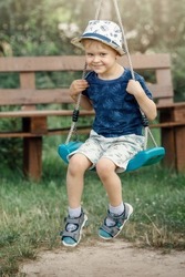 Very happy child to swing in the grandmother summer garden during the holidays.
