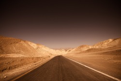 Dark, ominous road leading through desert of badlands Death Valley National Park