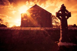 Ireland celtic cross at medieval church cemetery under fiery sky