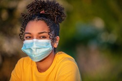 Mixed race African American teenager teen girl young woman wearing a face mask outside during the Coronavirus COVID-19 virus pandemic