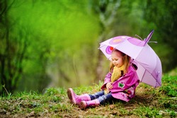 smiling little girl with umbrella in raincoat and boots outdoor