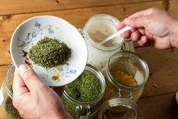 Middle Eastern cuisine: chef mixing spices and herbs to give flavour to the food. On the plate is dried parsley, the chef is dipping into the powdered garlic jar.