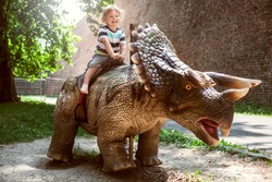 Little boy riding dinosaur in dino park