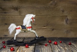 Vintage - old wooden rocking horse on a wooden old board for a christmas card with red balls - classic decoration