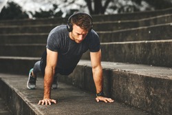 Young fit man doing push-ups outdoors on concrete steps