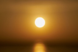 A blurry sun rising over the sea at dawn