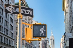 One way and crosswalk signs on a street in Manhattan with the New York City skyline in the background