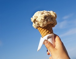 Ice cream cone held up to the hot summer sky