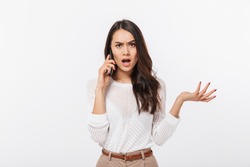 Portrait of a furious asian businesswoman talking on mobile phone isolated over white background