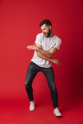 Photo of handsome young man dancing isolated over red wall background.