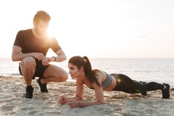 Attractive young sport couple doing plank exercise at the beach