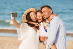 Happy family spending good time at the beach together, taking selfie