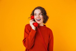 Image of emotional young pretty woman posing isolated over yellow wall background talking by telephone.