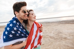 Happy friends spending time at the beach, holding american flag