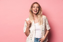 Image of happy beautiful blonde woman posing isolated over pink wall background showing copyspace pointing.