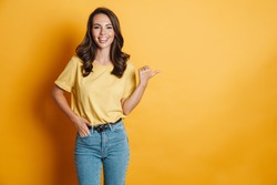 Image of joyful charming woman smiling and pointing finger aside isolated over yellow background