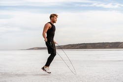 Image of caucasian athletic sportsman working out with jumping rope on nature