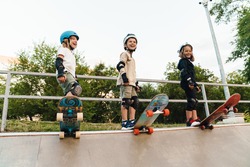 Happy kids on skateboards at the ramp, ready to ride down the ramp