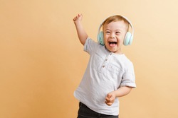 White boy with down syndrome in headphones laughing at camera isolated over beige background