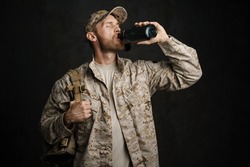 White military man wearing uniform drinking water from flask isolated over black wall