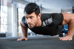 Portrait of a fitness man doing push ups in gym